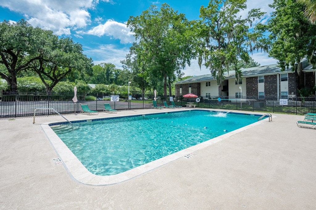 A swimming pool surrounded by a fence and trees at Brackenbrook Apartments, South Carolina