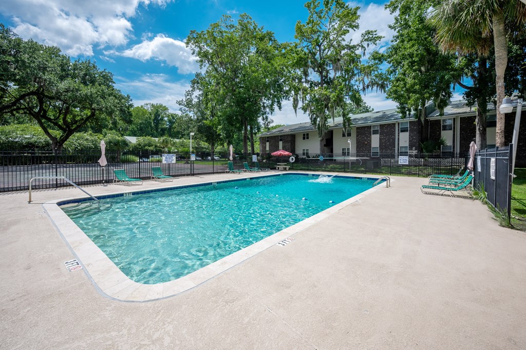 A swimming pool surrounded by a fence and trees at Brackenbrook Apartments, North Charleston, South Carolina
