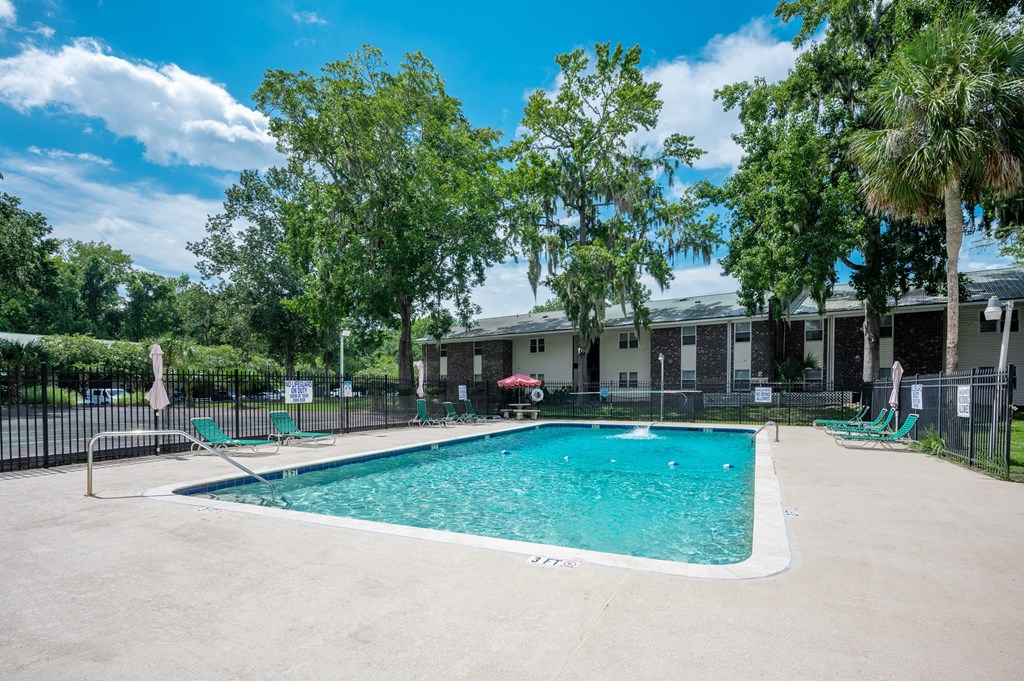 A swimming pool surrounded by trees and a fence at Brackenbrook Apartments, North Charleston, SC, 29418