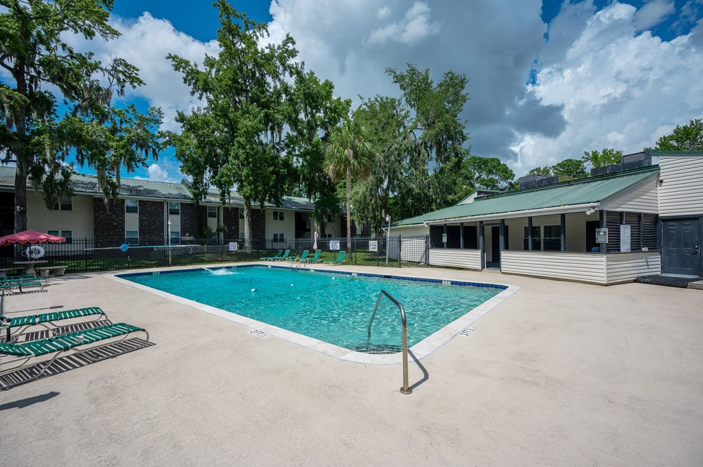 A swimming pool surrounded by trees and buildings at Brackenbrook Apartments, North Charleston, South Carolina