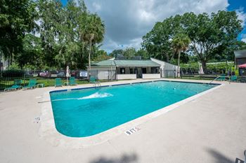 A large outdoor swimming pool surrounded by a fence and trees at Brackenbrook Apartments, North Charleston