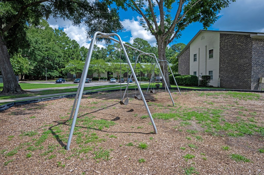 A playground with a swing set in the middle of a grassy area at Brackenbrook Apartments, South Carolina