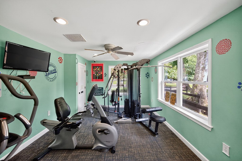 A gym with a green wall and a television at Brackenbrook Apartments, North Charleston, SC, 29418
