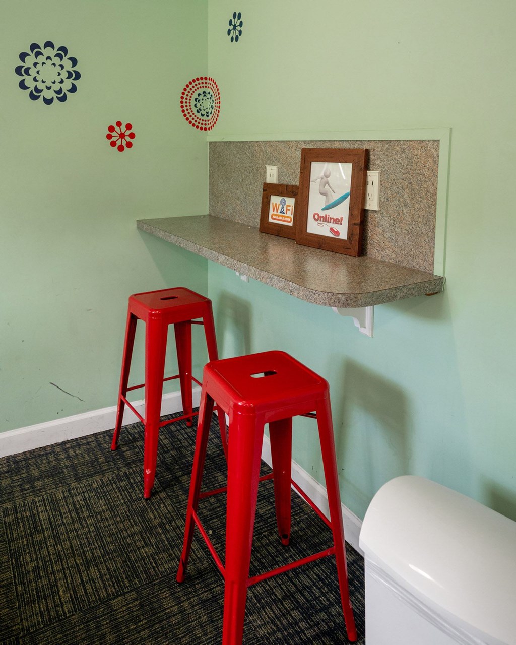 Two red stools are in front of a counter with a picture of a bird and a sign at Brackenbrook Apartments, South Carolina