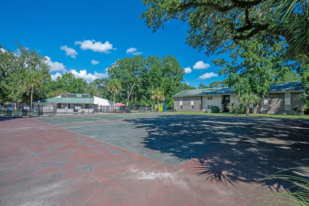 A basketball court is surrounded by trees and buildings at Brackenbrook Apartments, North Charleston, SC, 29418