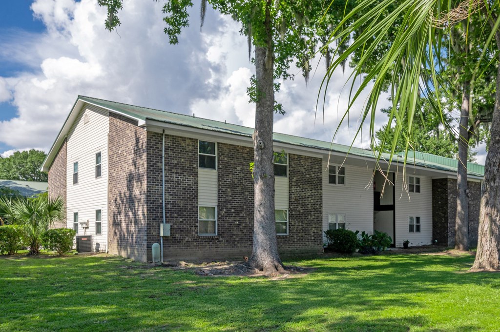 A brick house with a green roof and a white door at Brackenbrook Apartments, North Charleston, SC, 29418