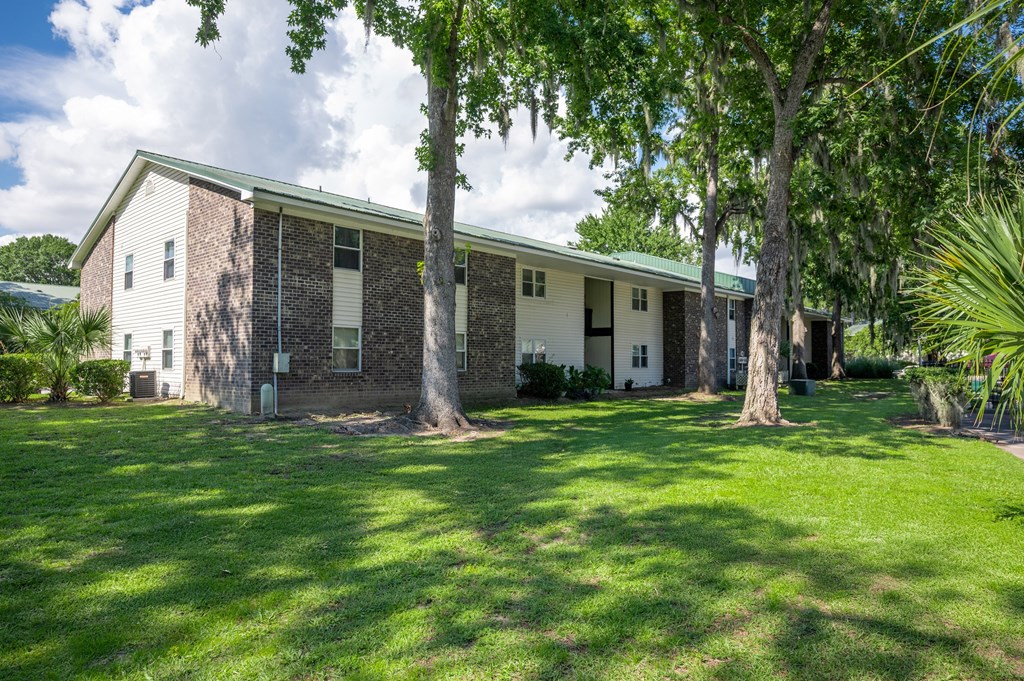 A white building with a green roof is surrounded by trees and grass at Brackenbrook Apartments, South Carolina, 29418