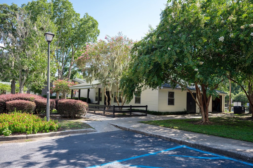 A white house is surrounded by green trees and bushes at Brackenbrook Apartments, South Carolina
