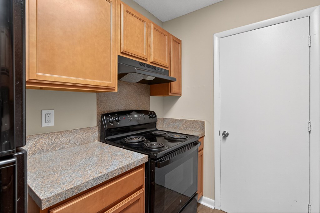 A kitchen with a black stove top oven and a white door at Brackenbrook Apartments, North Charleston, SC