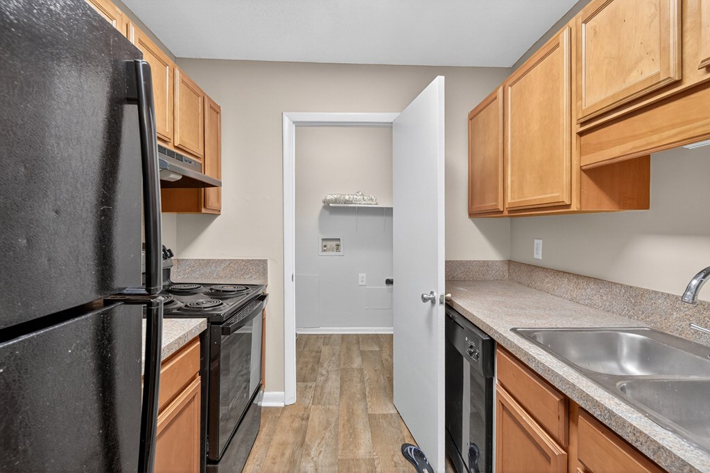 A kitchen with a black refrigerator and wooden cabinets at Brackenbrook Apartments, South Carolina, 29418