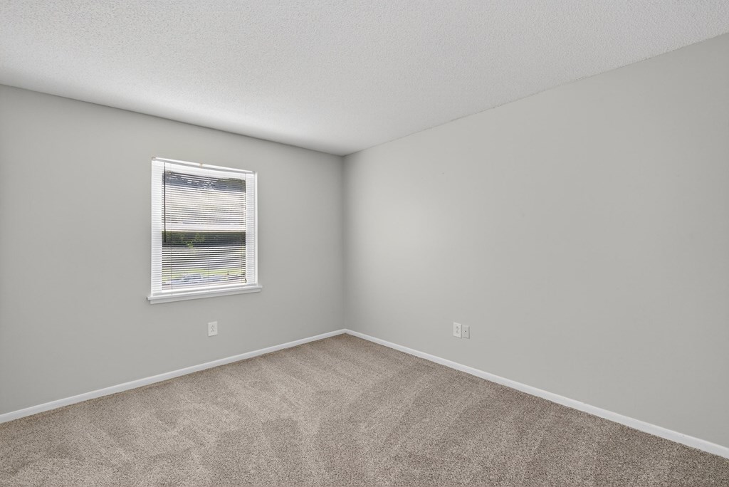 A room with a carpeted floor and a window with blinds at Brackenbrook Apartments, South Carolina