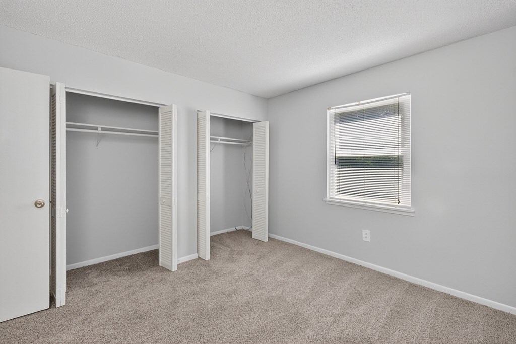 A room with a carpeted floor and a window with blinds at Brackenbrook Apartments, North Charleston, South Carolina