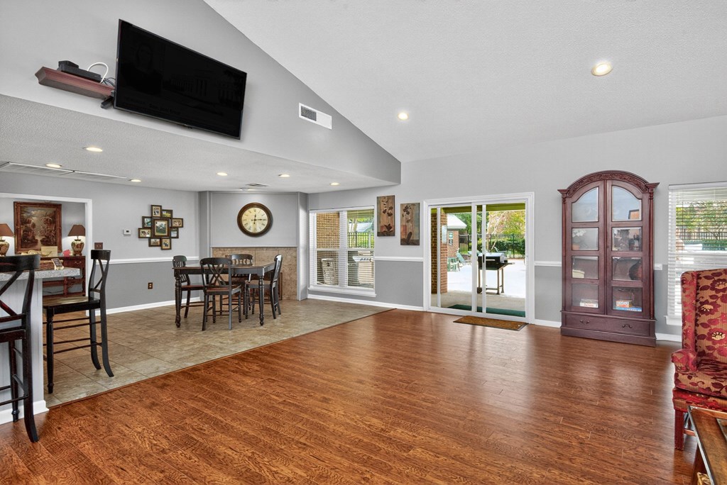 A living room with a wooden floor and a flat screen TV mounted on the wall at North Bluff Apartments, North Charleston, South Carolina