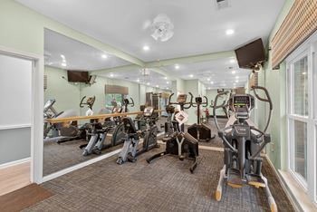 A gym with a variety of exercise equipment including treadmills, stationary bikes, and weight machines at North Bluff Apartments, South Carolina