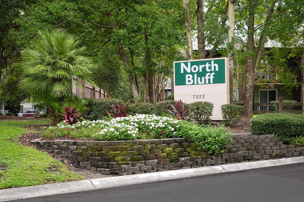 A sign that says North Bluff stands in front of a flower bed at North Bluff Apartments, North Charleston 29406