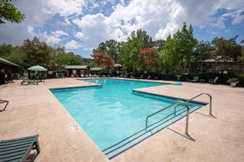 A large swimming pool surrounded by trees and a fence at North Bluff Apartments, South Carolina