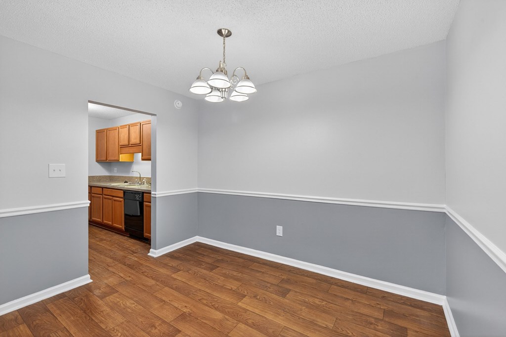 A room with wooden floors and a kitchen area in the background at North Bluff Apartments, North Charleston
