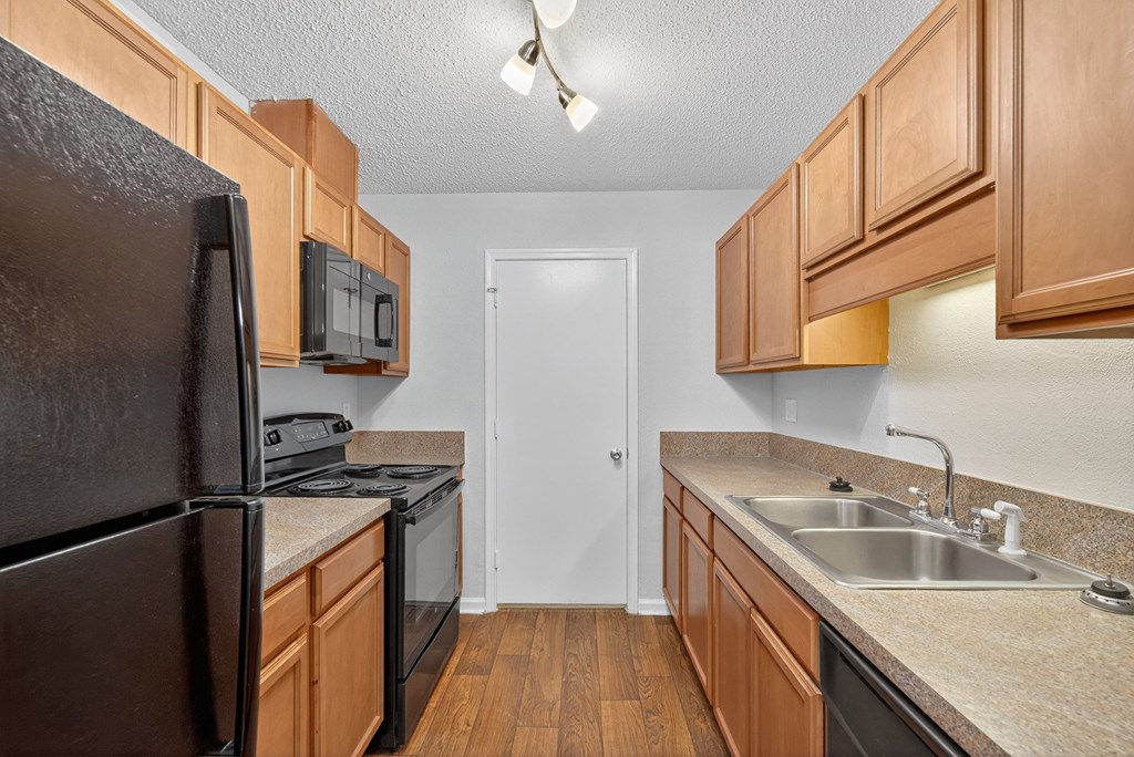A kitchen with wooden cabinets and a black refrigerator at North Bluff Apartments, South Carolina, 29406
