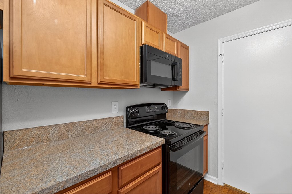 A kitchen with wooden cabinets and a black stove top oven at North Bluff Apartments, North Charleston, SC, 29406