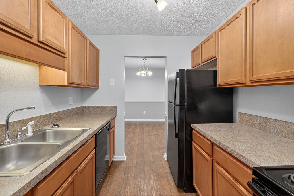 A kitchen with wooden cabinets and a black refrigerator at North Bluff Apartments, South Carolina