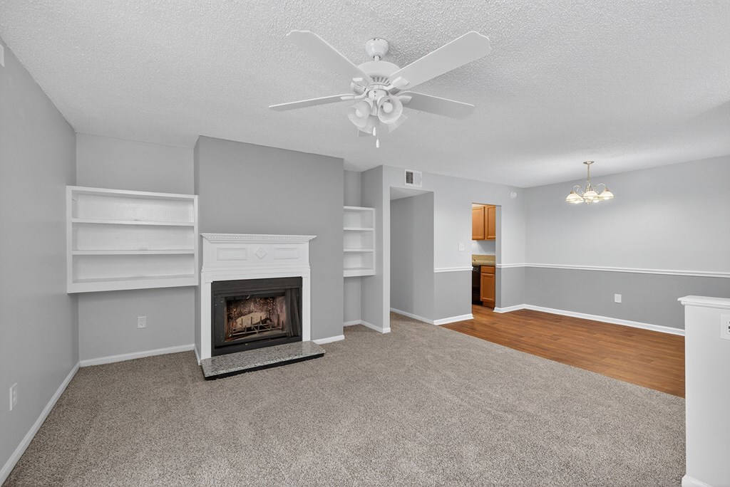 A living room with a fireplace and a ceiling fan at North Bluff Apartments, North Charleston, SC