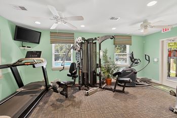 A gym with a treadmill, elliptical trainer, and a stationary bike at Sawbranch Apartments, South Carolina, 29485