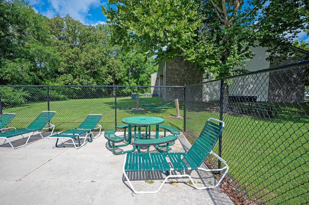 A green picnic table and chairs are set up in a fenced-in area at Sawbranch Apartments, Summerville, South Carolina