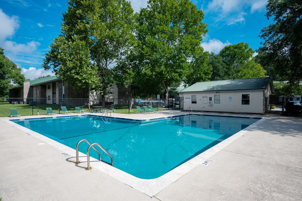 A large swimming pool surrounded by trees and buildings at Sawbranch Apartments, Summerville, SC