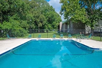 A swimming pool surrounded by trees and chairs at Sawbranch Apartments, Summerville, SC, 29485