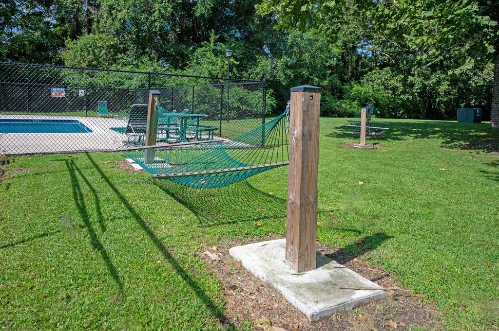 A wooden post stands in a grassy area next to a pool and picnic table at Sawbranch Apartments, Summerville, South Carolina