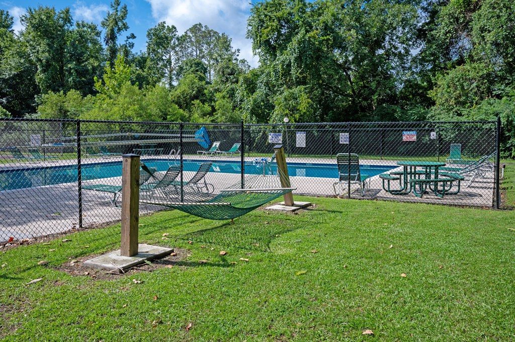 A pool area with a fence and a table and chairs at Sawbranch Apartments, South Carolina