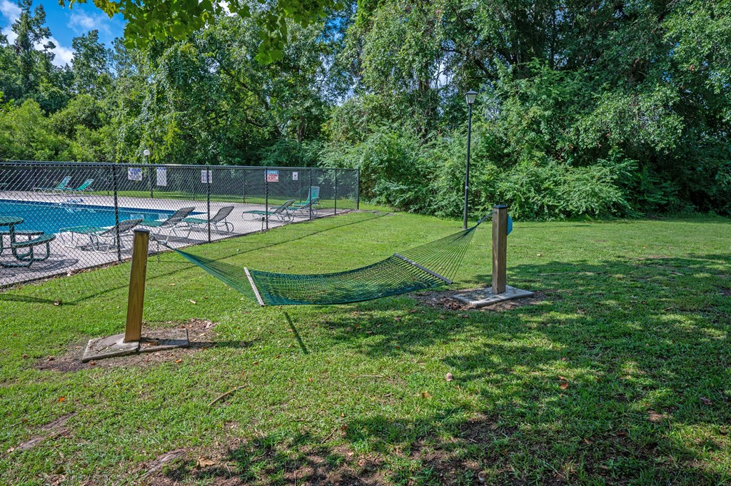 A tennis court is surrounded by a fence and trees at Sawbranch Apartments, South Carolina, 29485