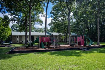 A playground with a green slide and red and green swings at Sawbranch Apartments, Summerville