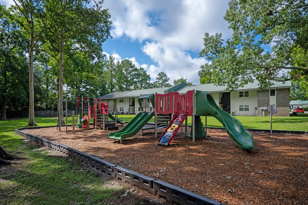 A playground with a green slide and red and green swings at Sawbranch Apartments, Summerville, SC