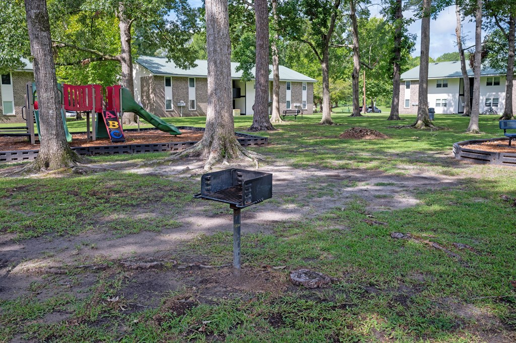 A black mailbox sits on a grassy area in front of a playground and houses at Sawbranch Apartments, South Carolina