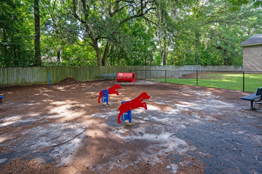 A playground with red and blue slides and a green bench at Sawbranch Apartments, Summerville