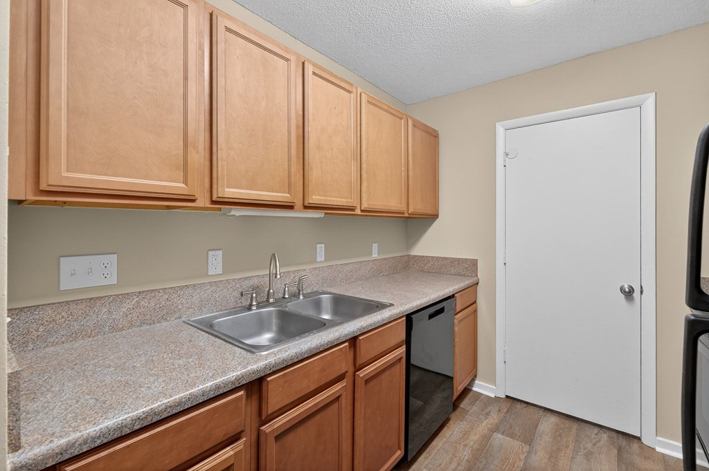 A kitchen with wooden cabinets and a white door at Sawbranch Apartments, South Carolina