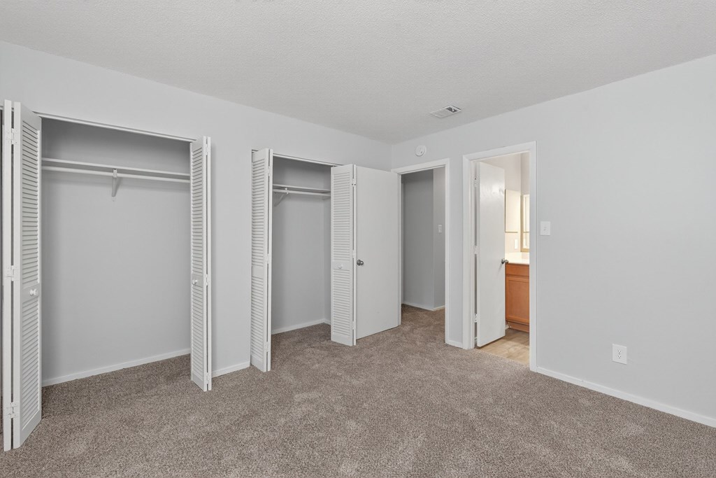 A room with white walls and carpeted floor with three open closets at Sawbranch Apartments, Summerville 29485