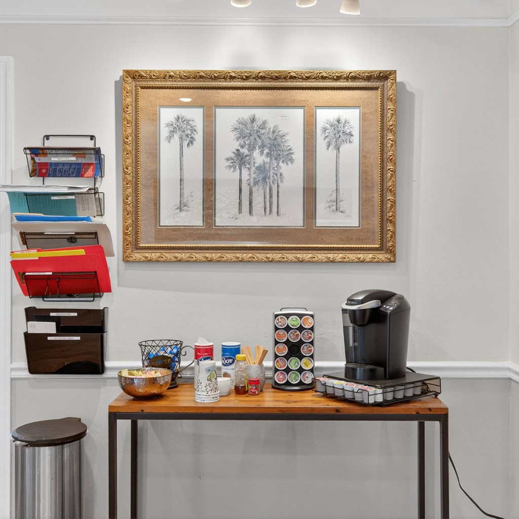 A coffee maker is on a table with a bowl, a cup, and a canister of straws at The Landing Townhomes Apartments, Hanahan 29410