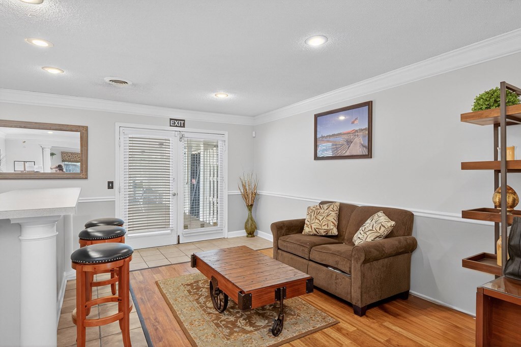 A living room with a brown couch, a wooden coffee table, and a painting on the wall at The Landing Townhomes Apartments, Hanahan, SC
