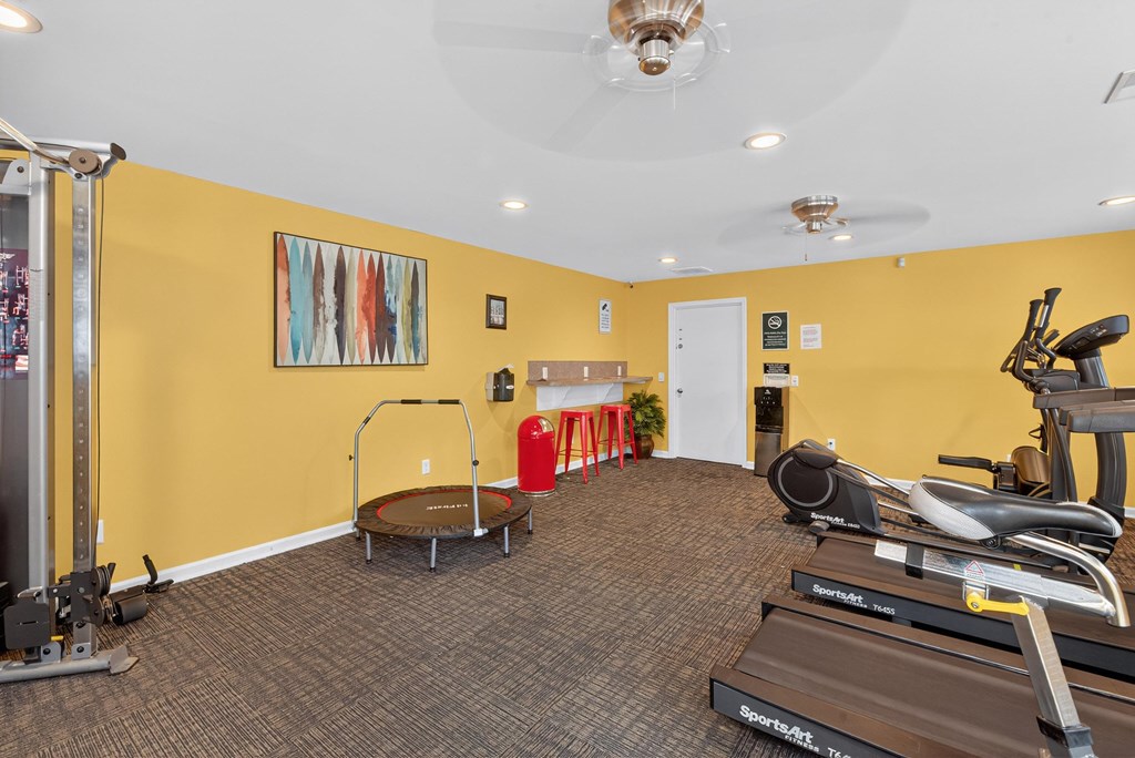 A gym with a variety of equipment including a treadmill, elliptical trainer, and a trampoline at The Landing Townhomes Apartments, Hanahan, South Carolina