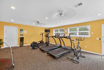 A spacious gym with a variety of equipment including treadmills, elliptical machines, and a stationary bike at The Landing Townhomes Apartments, Hanahan