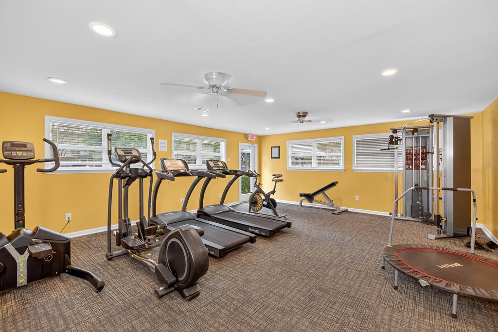 A gym with a variety of exercise equipment including treadmills, elliptical machines, and a stationary bike at The Landing Townhomes Apartments, Hanahan
