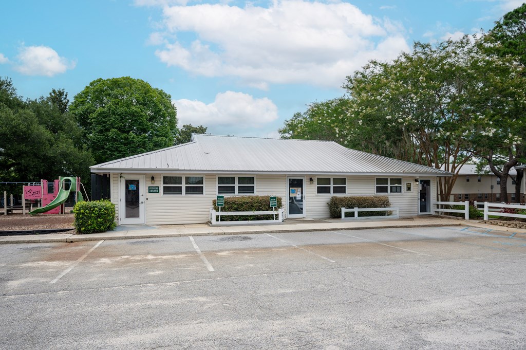 A small white building with a grey roof and a parking lot in front at The Landing Townhomes Apartments, Hanahan 29410