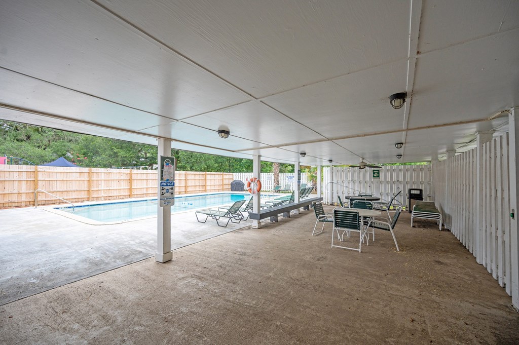 A covered outdoor area with a pool and chairs at The Landing Townhomes Apartments, Hanahan
