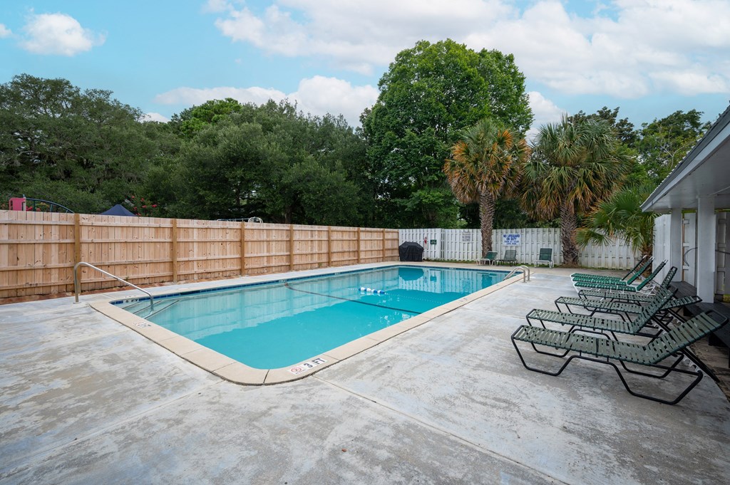 A pool with a fence around it and chairs on the side at The Landing Townhomes Apartments, Hanahan, South Carolina