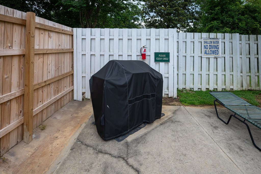 A black covered object is in front of a white fence with a sign  at The Landing Townhomes Apartments, South Carolina, 29410