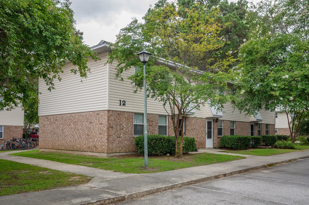 A street lamp stands in front of a brick building with a green tree to the left at The Landing Townhomes Apartments, Hanahan, South Carolina