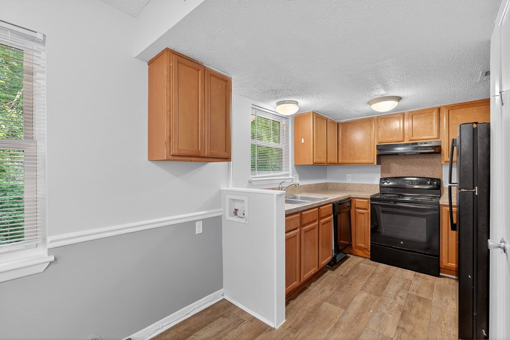 A kitchen with wooden cabinets and black appliances at The Landing Townhomes Apartments, Hanahan, SC