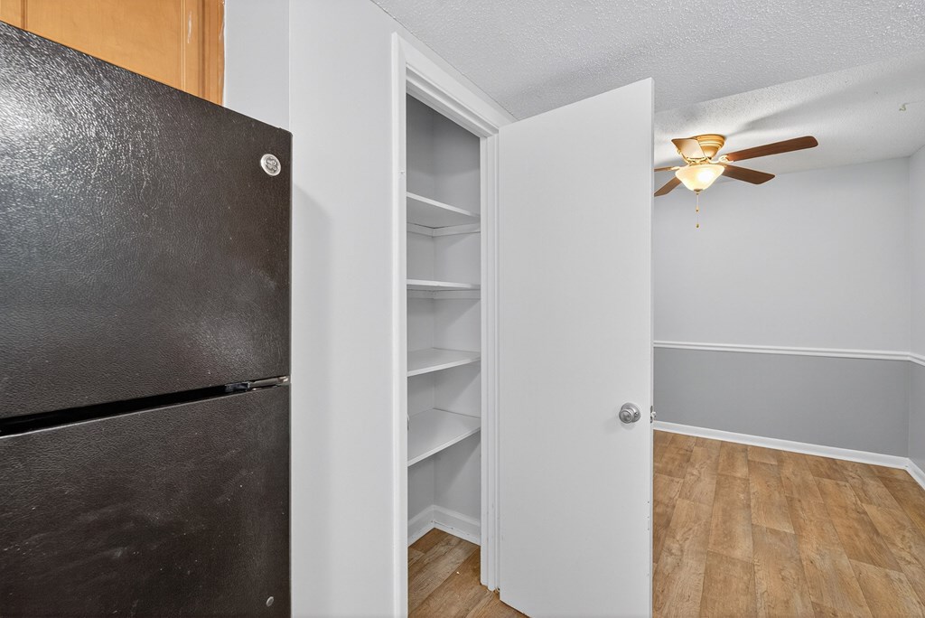 A black refrigerator is next to an open white door at The Landing Townhomes Apartments, Hanahan, South Carolina